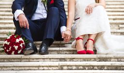 Ein Ehepaar sitzt an seinem Hochzeitstag auf den Stufen einer Kirche